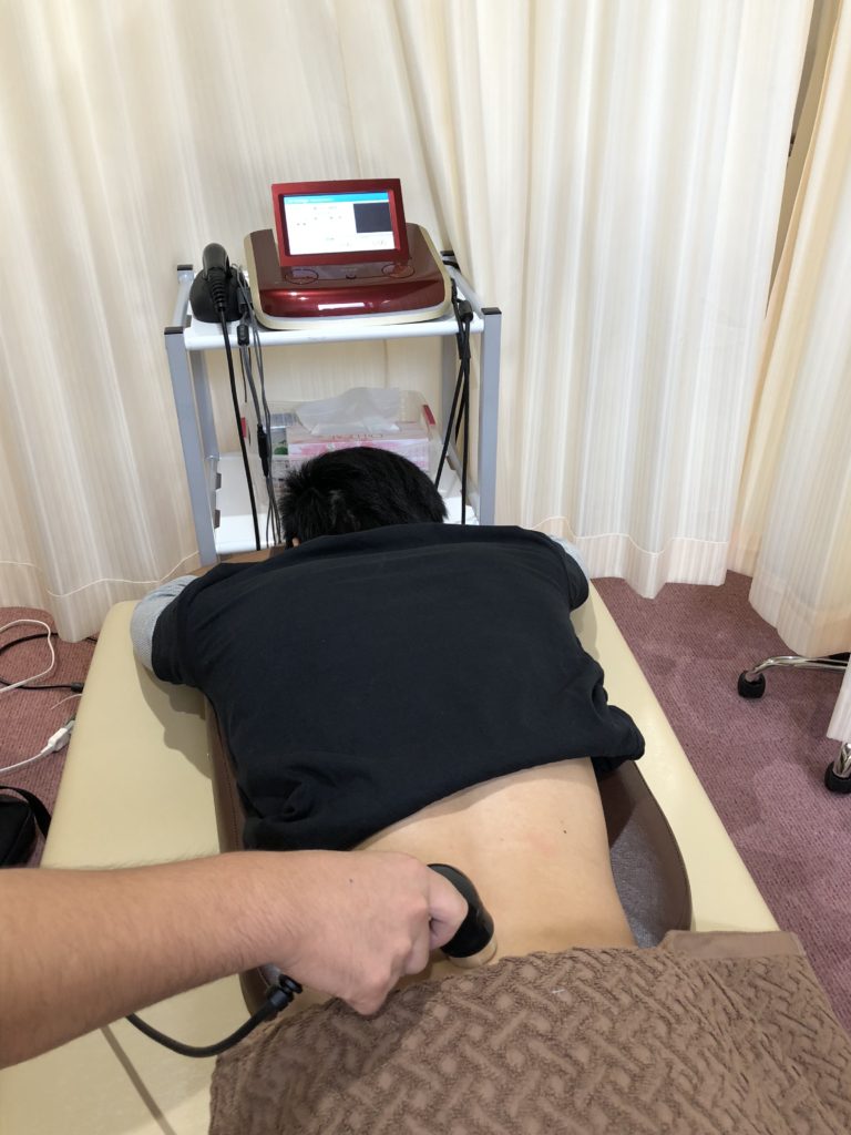 神戸三田やわら整骨院・整体院でぎっくり腰の患者様をハイボルテージ療法で施術している様子。